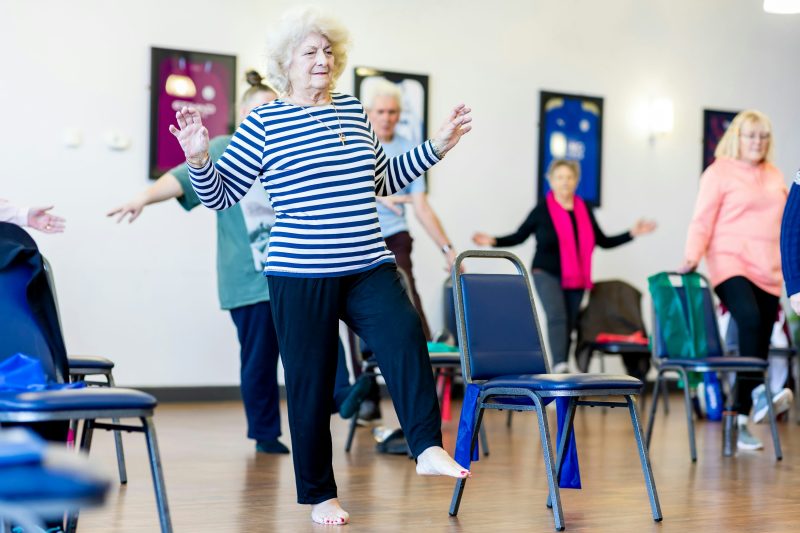 Older adults practicing standing balance exercises in a group fitness setting
